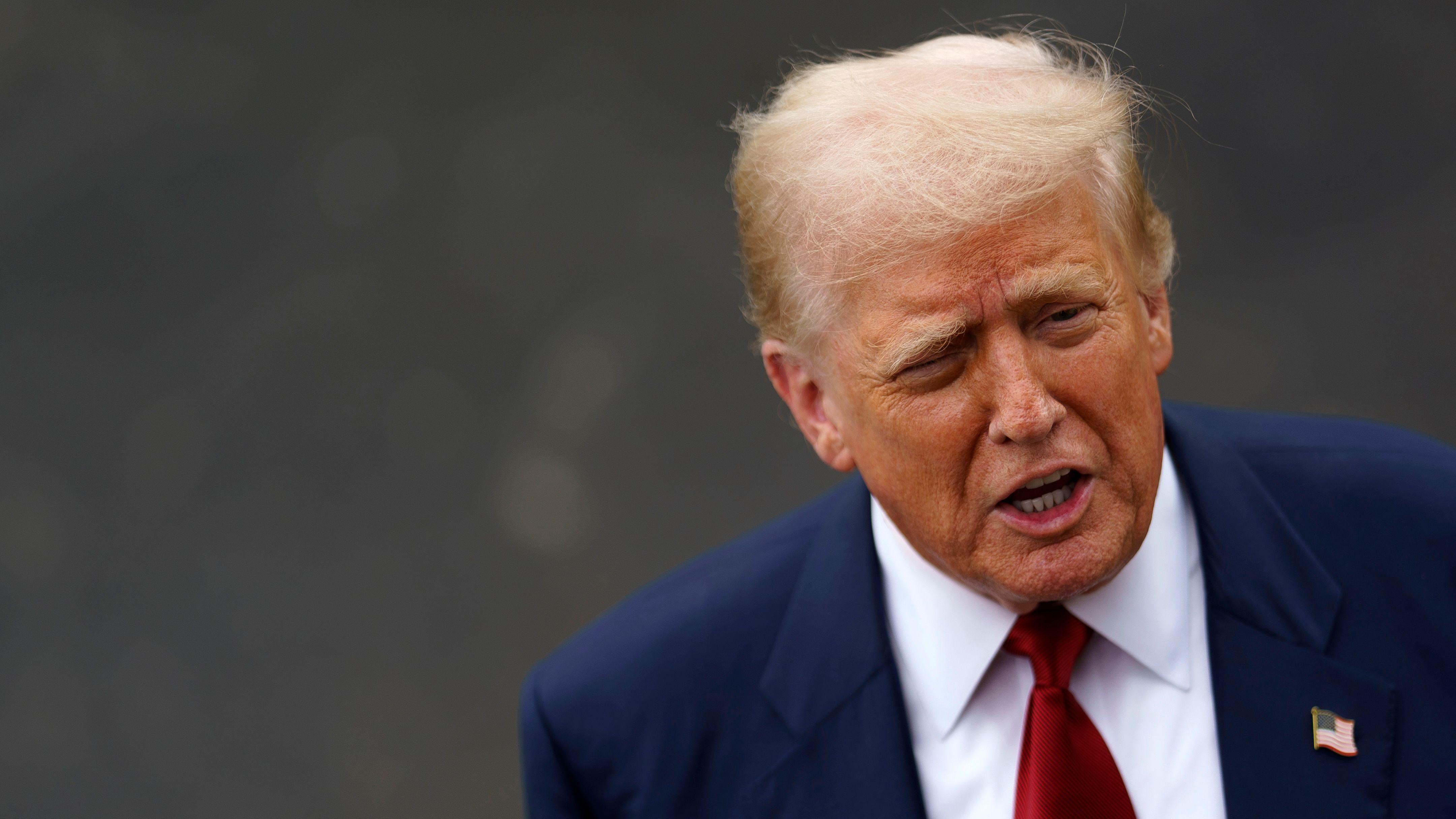 O presidente americano Donald Trump, de terno azul e gravata vermelha