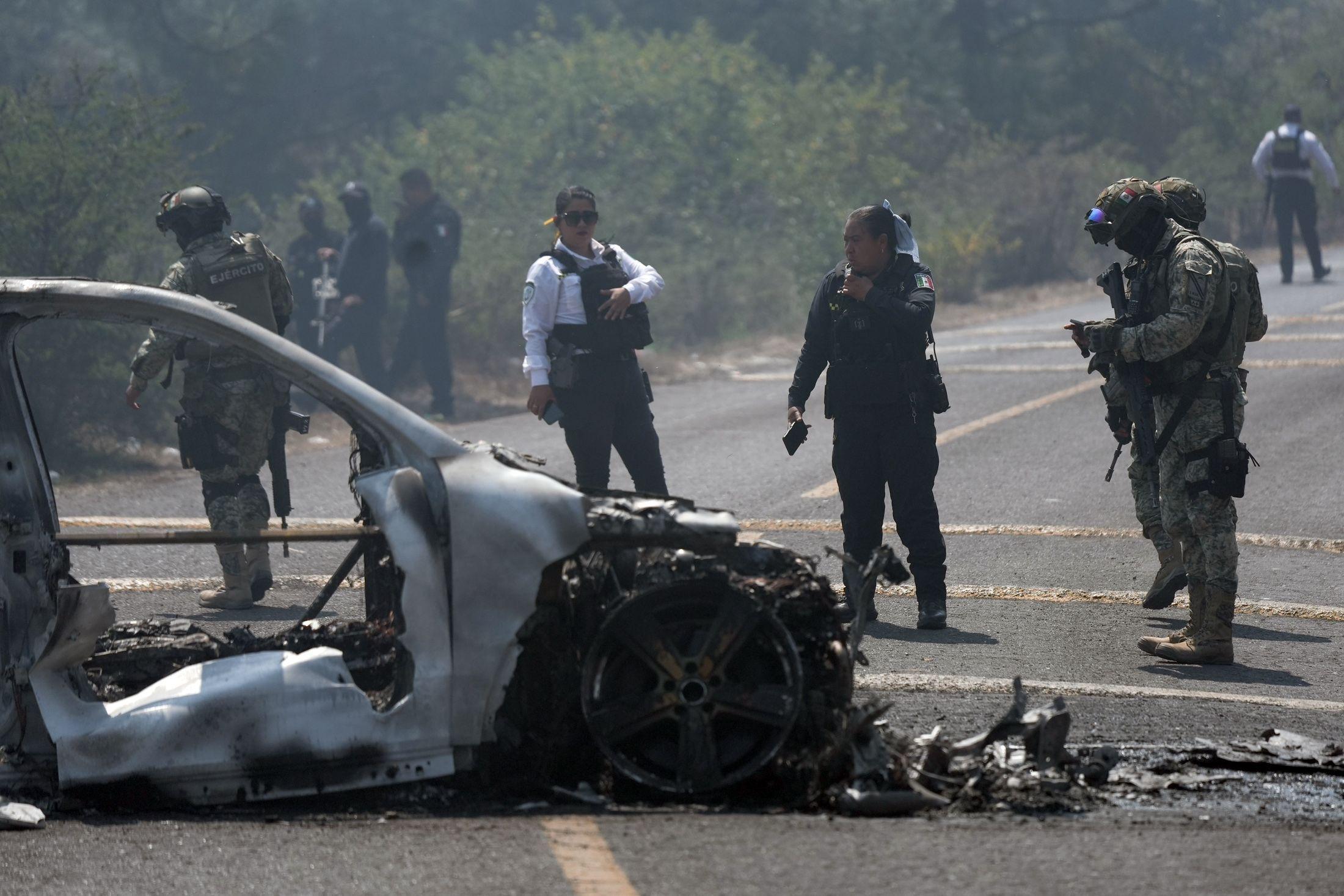 Agentes inspeccionan un vehículo quemado en México.
