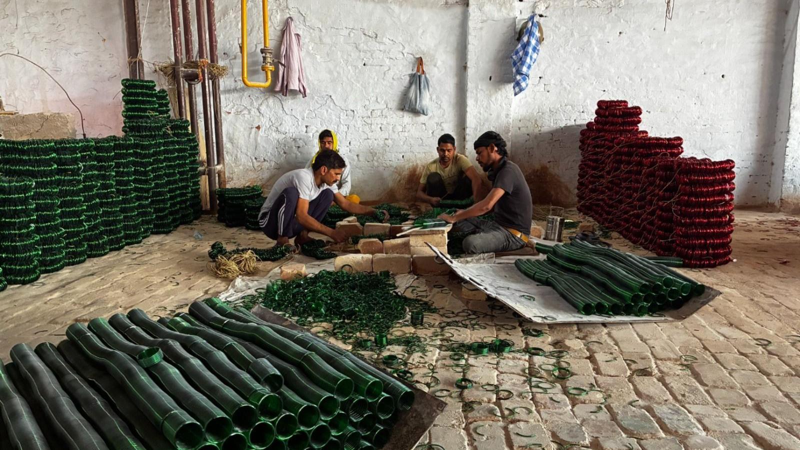 Four men sit and make dark green and red bangles in one of the factories in Firozabad