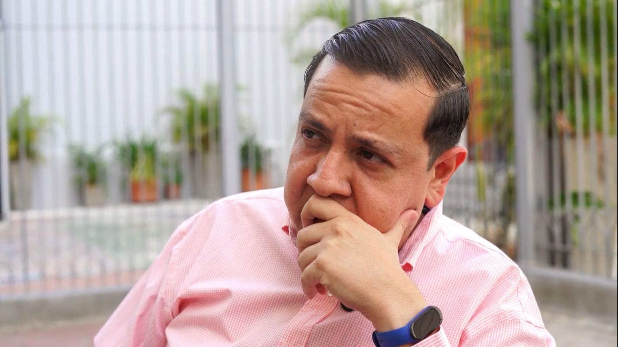 Javier Tarazona pensativo, con una camisa rosada y blanca y un reloj azul. 