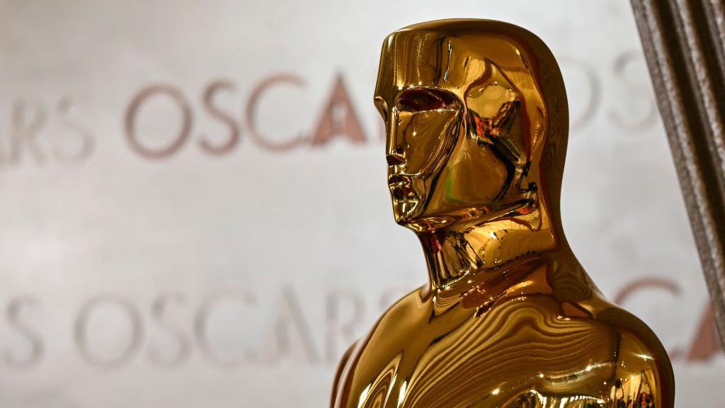 Primer plano de una estatuilla de los Oscar con el nombre de los premios escrito en el fondo en el teatro Dolby de Hollywood, Los Ángeles, California, Estados Unidos, el 28 de febrero de 2025. 