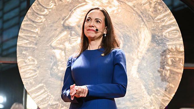 María Corina Machado, vistiendo un vestido azul.