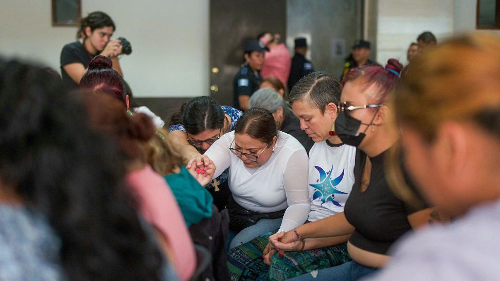 Mujeres se agarran las manos y rompen en llanto durante la audiencia de sentencia del caso Hogar Seguro, donde un incendio dejó el 8 de marzo de 2017 41 adolescentes muertas y 15 con quemaduras graves, en el Séptimo Tribunal en la Ciudad de Guatemala el 12 de agosto de 2025.  (Foto de EDWIN BERCIAN/AFP a través de Getty Images)