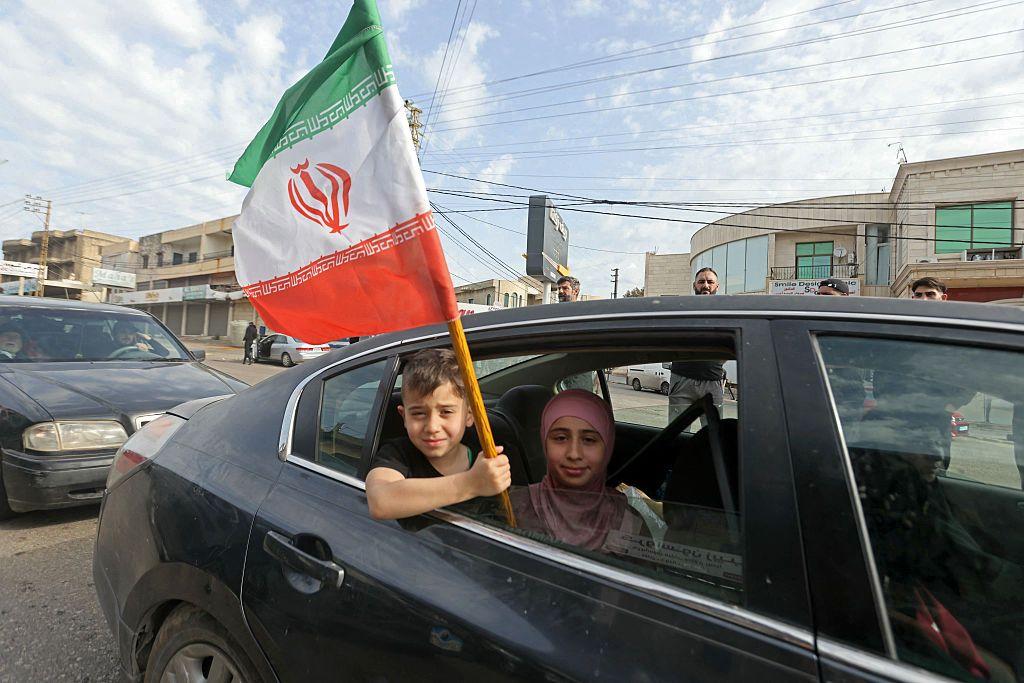 Seorang anak laki-laki memegang bendera Iran saat ia kembali ke kota Marwanieh di Lebanon selatan pada 17 April 2026. Kesepakatan gencatan senjata 10 hari antara Lebanon dan Israel mulai berlaku pada 17 April, membuat warga yang mengungsi berbondong-bondong kembali ke selatan menuju rumah mereka, meskipun tentara Lebanon memperingatkan adanya 