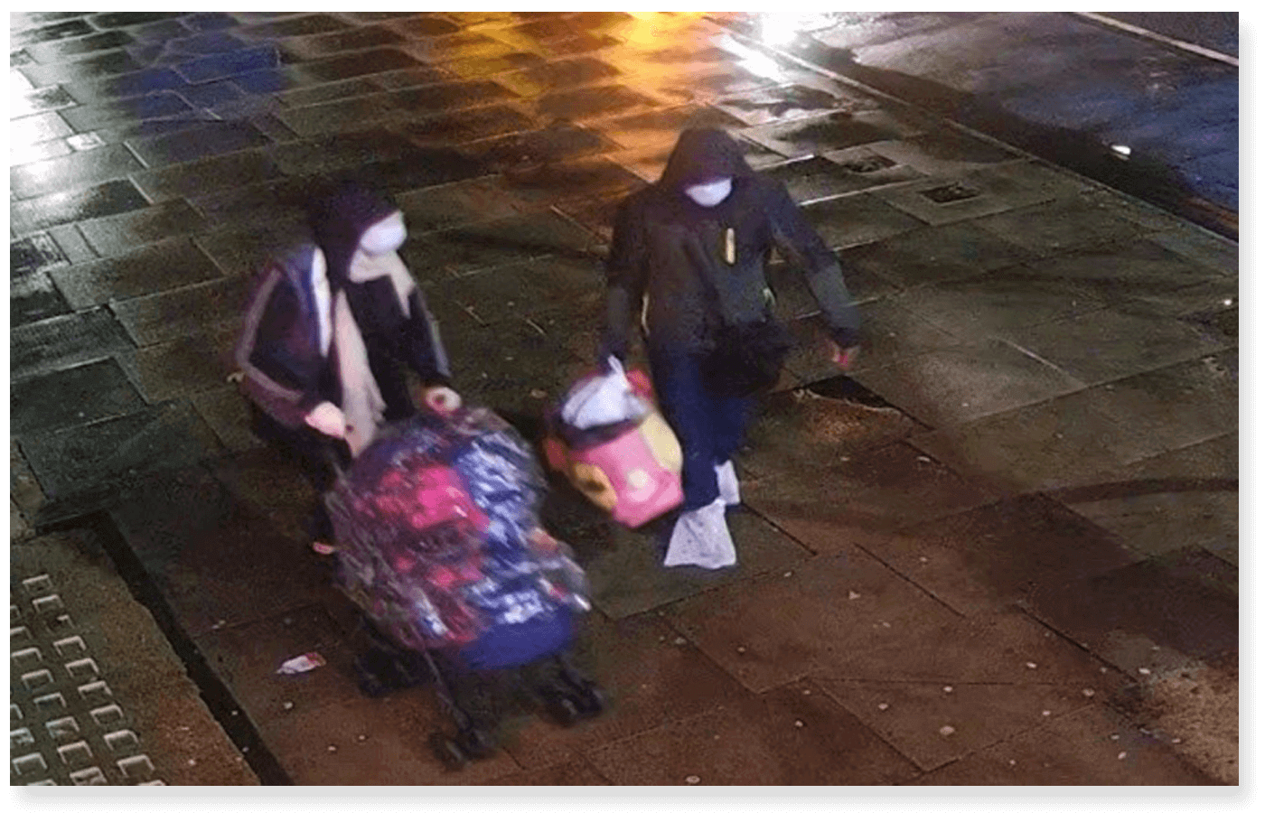 Imagem de câmera de segurança mostra casal de capuz e máscara facial carregando uma sacola e carrinho de bebê