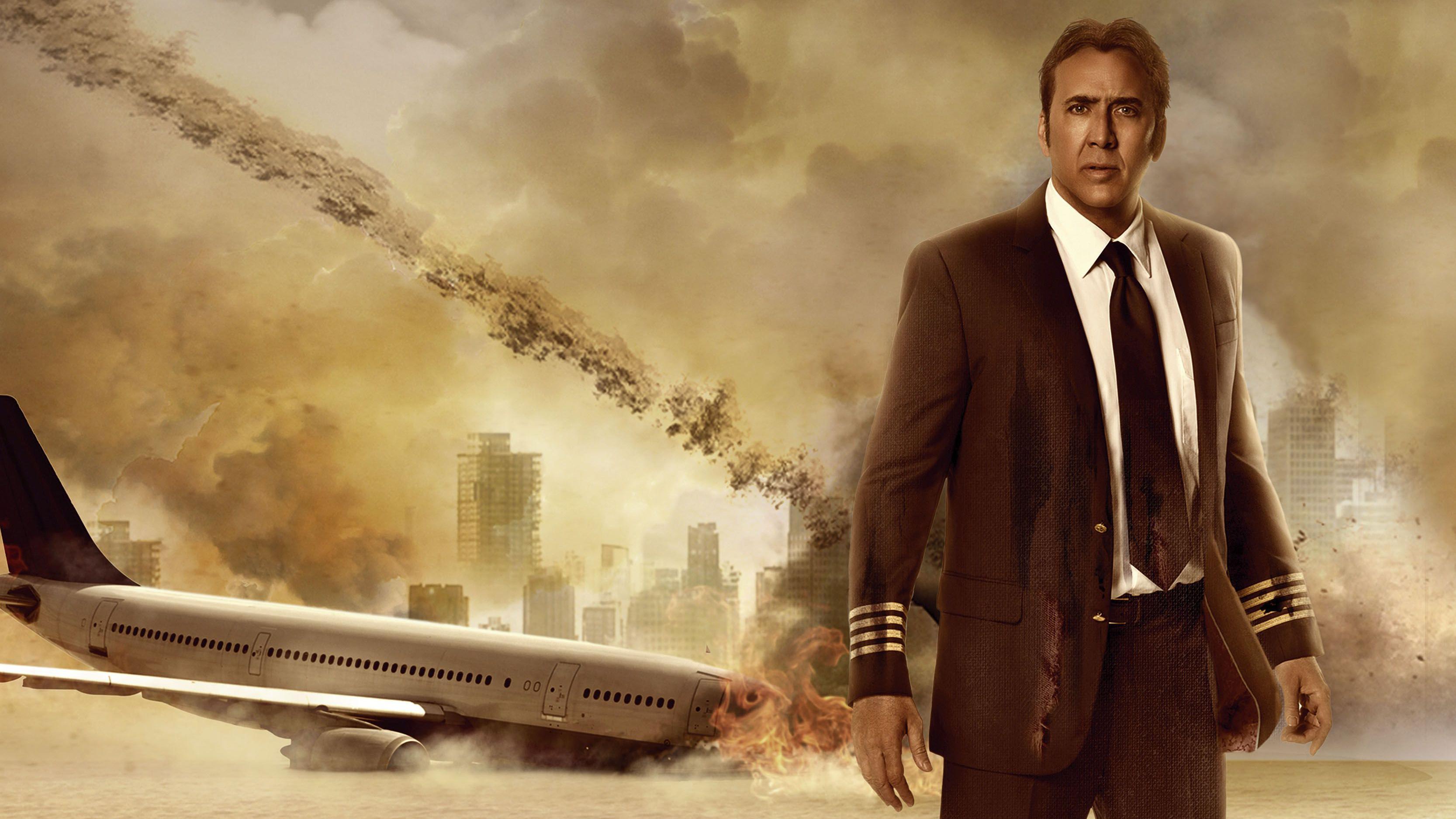 Uma imagem composta promocional mostrando Nicolas Cage em uniforme de piloto em pé na frente de um avião acidentado
