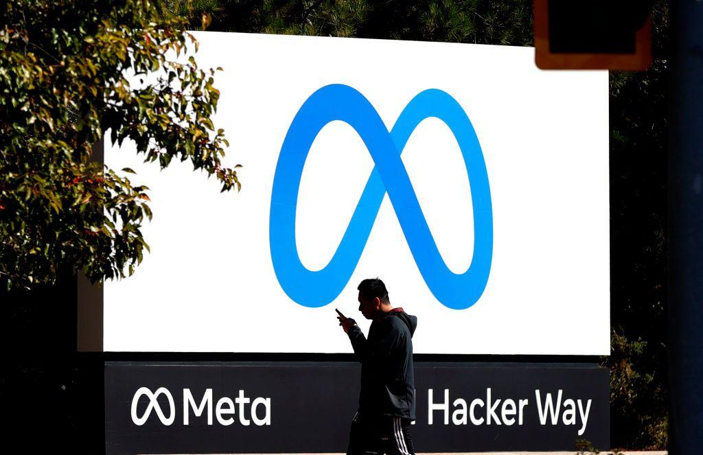Un peatón camina frente a un nuevo logotipo y el nombre «Meta» en el letrero situado ante la sede de Facebook.