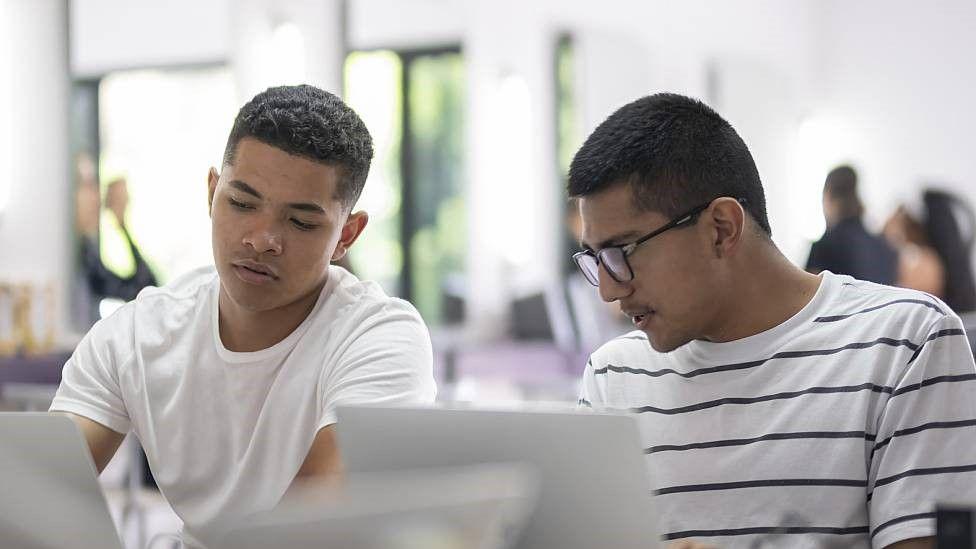 Dos jóvenes frentes a sus computadoras