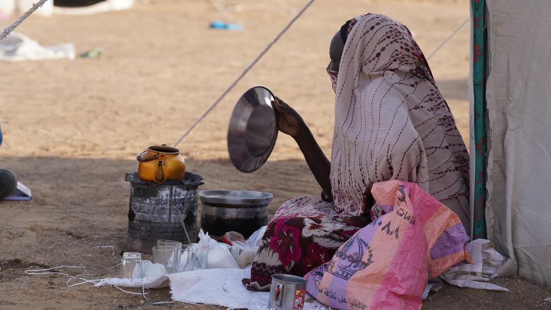 سيدة تقف أمام خيمة وتحمل وعاء