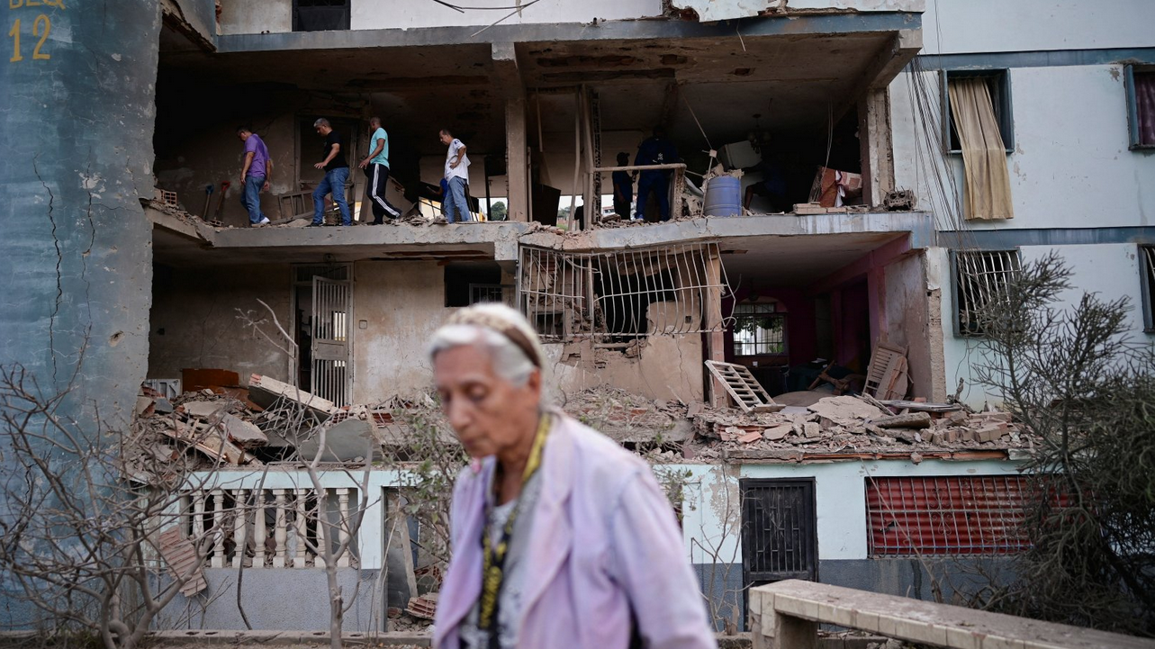 Žena ispred zgrade koja je pogođena projektilom
