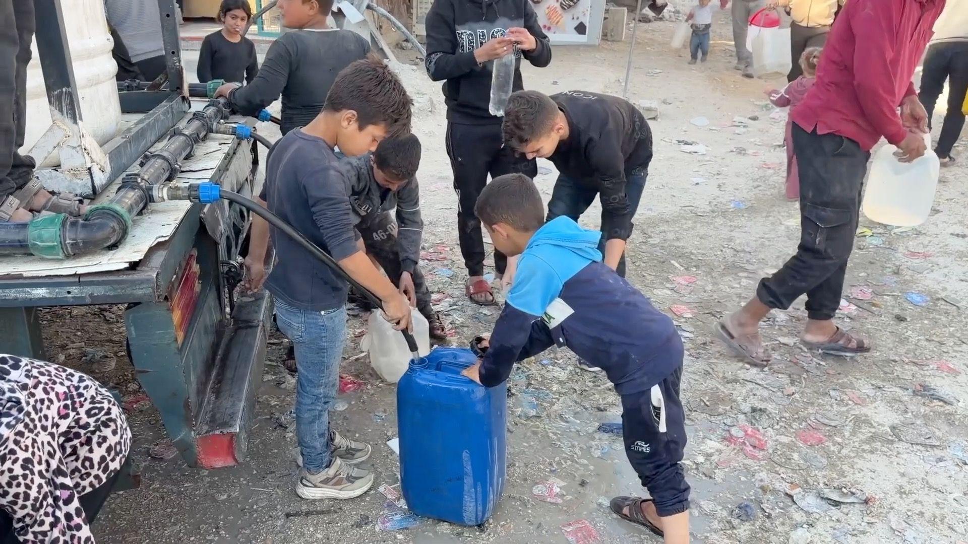 مجموعة من الأطفال ينتظرون دورهم لتعبئة المياه.
