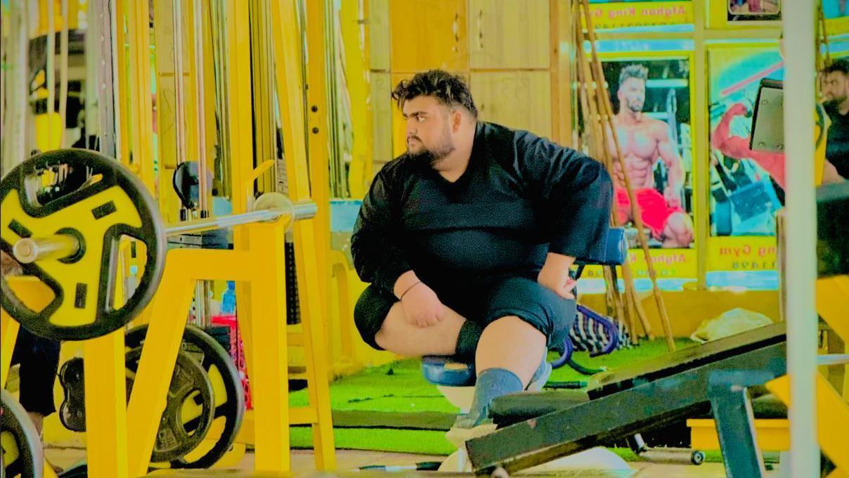 Qudratullah wearing a black shirt and sitting in a gym
