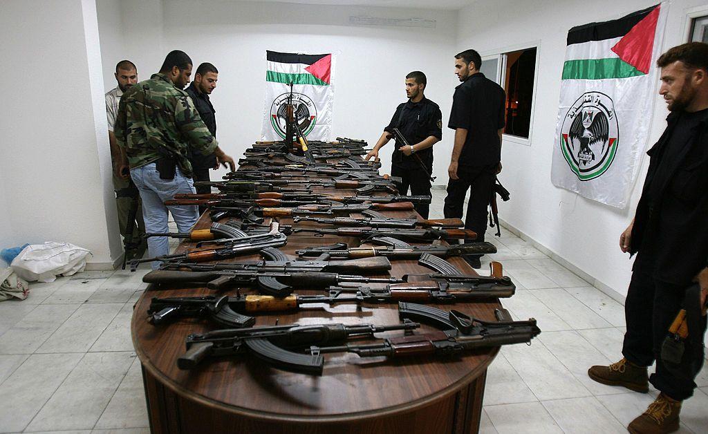 مجموعة من الرجال أمام طاولة عليها العديد من الأسلحة