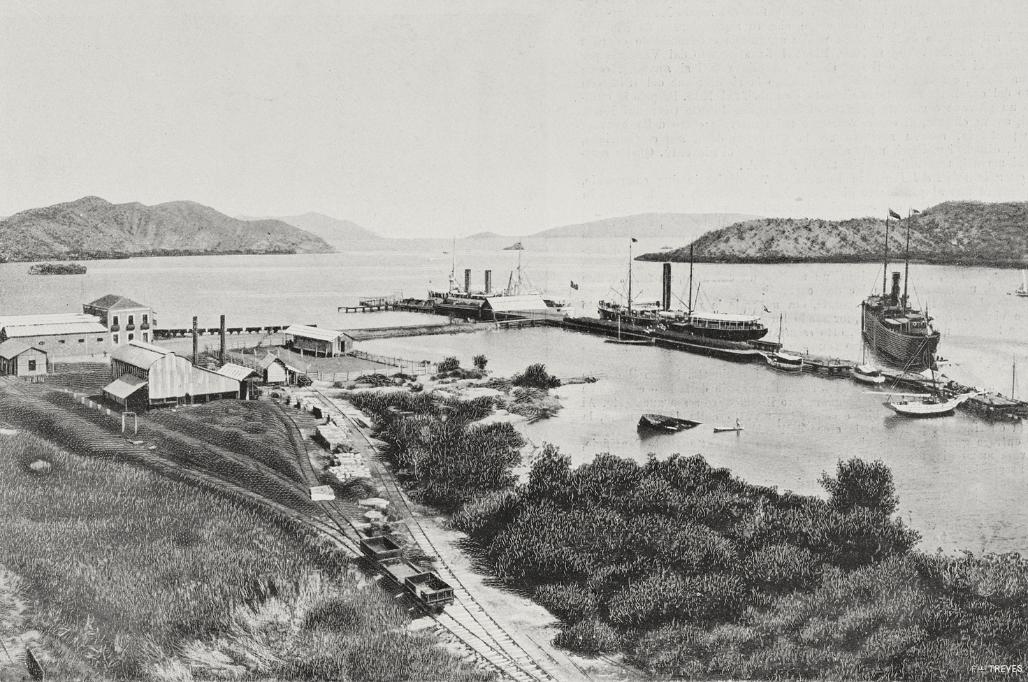 El puerto con unas pocas embarcaciones, líneas ferroviarias y casas pequeñas en medio de la vegetación