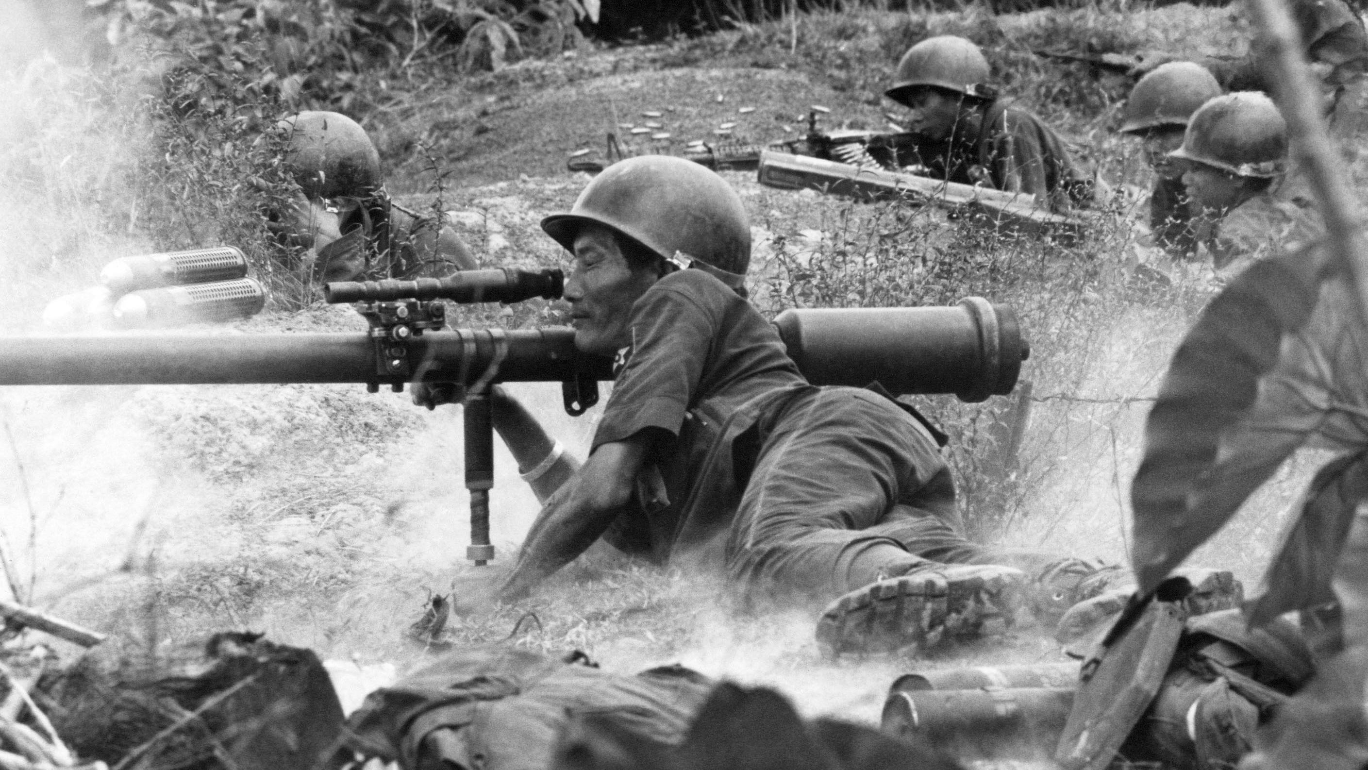 Imagen de un soldado de la guerra de vietnam en el frente de batalla. Está en el suelo y apunta con un arma.