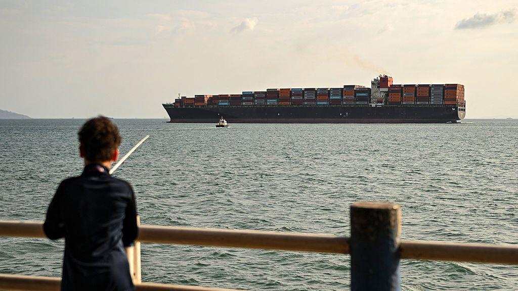 El buque portacontenedores Navios Constellation navega bajo bandera liberiana frente a un niño que pesca en Ciudad de Panamá.