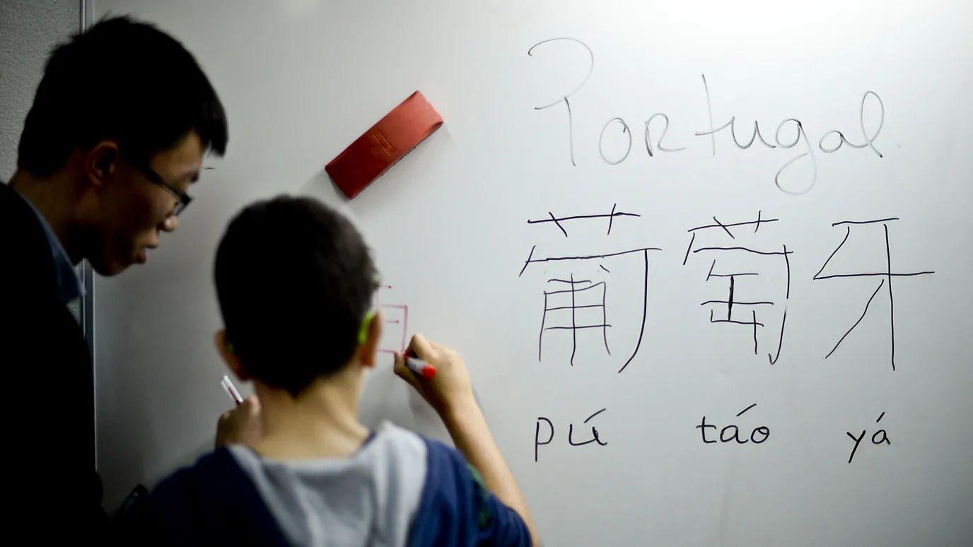 左邊男性在教一位小朋友書寫中文字