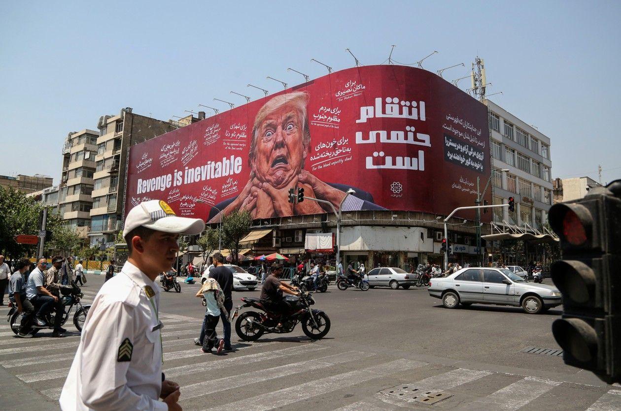 إيرانيون يمرون قرب لوحة تستهدف الرئيس الأمريكي دونالد ترامب عند تقاطع شارعي جمهوري وولي عصر في طهران، في 28 يوليو/تموز 2026.