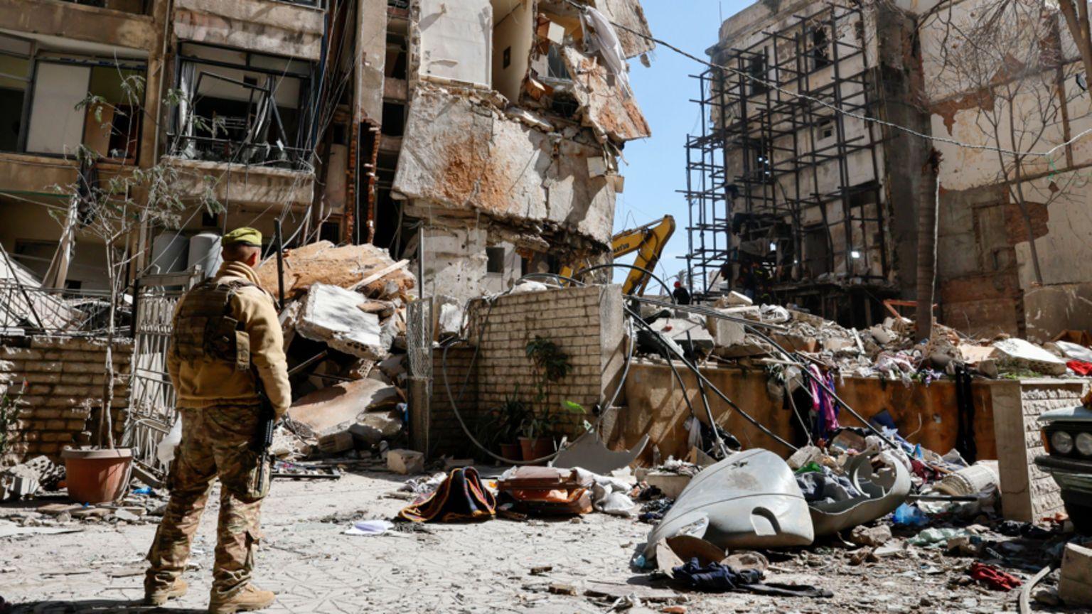 Un soldado mirando restos de un edificio bombardeado. 