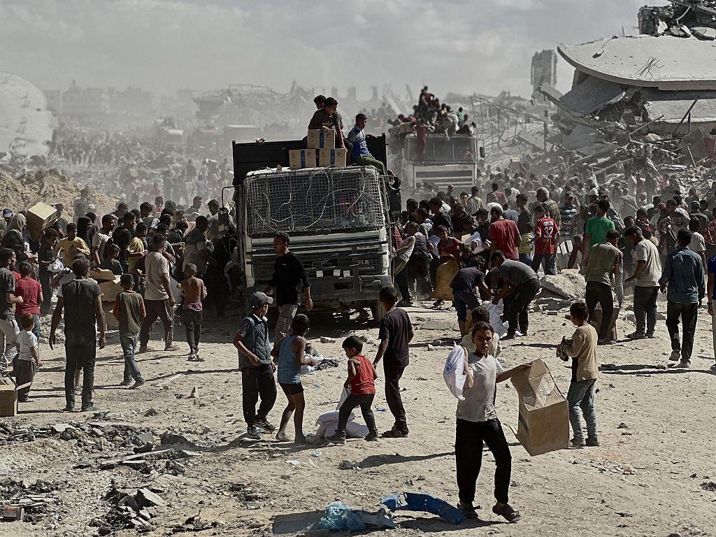 Warga Gaza membawa karung tepung dan kotak-kotak perlengkapan saat berkumpul di tengah reruntuhan untuk mengumpulkan bantuan kemanusiaan di Khan Yunis, Jalur Gaza, pada 12 Oktober 2025.