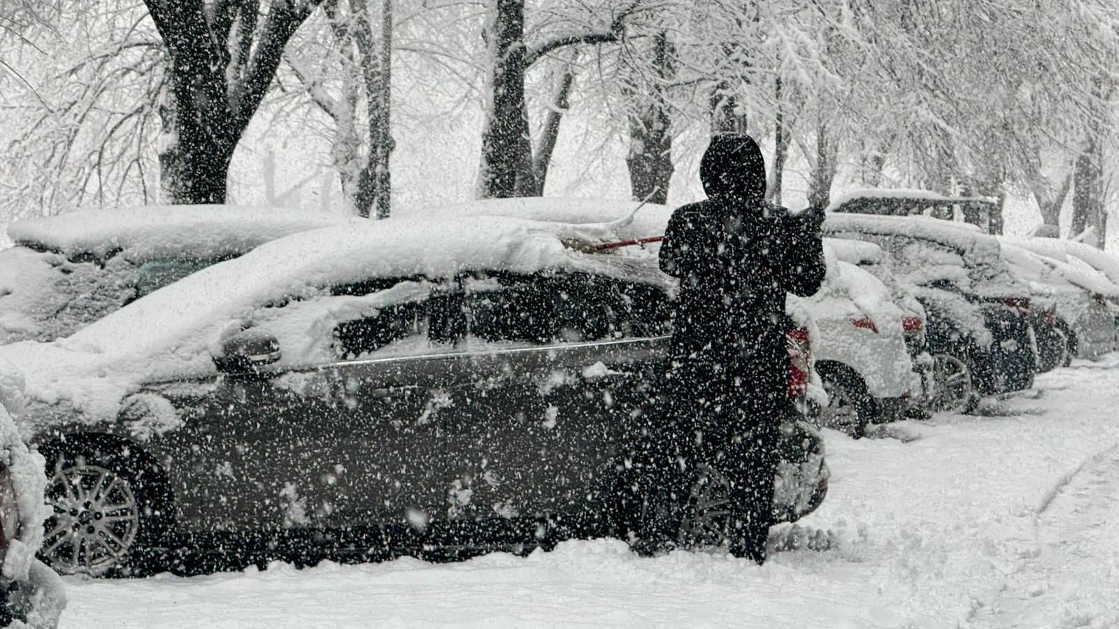 Čovek stoji pored automobila dok pada sneg u Sarajevu
