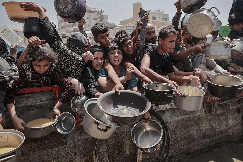 Palestinos, incluidos niños, que tienen dificultades para acceder a alimentos debido al bloqueo de Israel y los continuos ataques a la Franja de Gaza, esperan en fila para recibir comidas calientes distribuidas por la organización benéfica en la ciudad de Gaza, Gaza, el 30 de julio de 2025.
