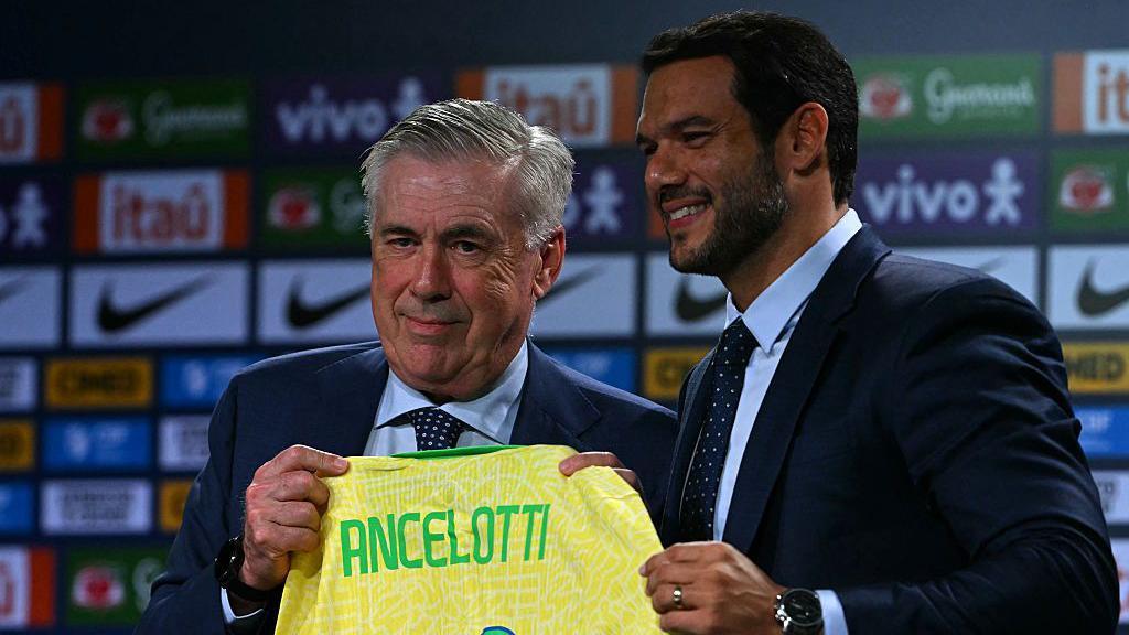 O novo técnico da seleção brasileira de futebol, o italiano Carlo Ancelotti (E), recebe a camisa do time das mãos do presidente da Confederação Brasileira de Futebol (CBF), Samir Xaud, durante sua apresentação oficial em um hotel na Barra da Tijuca, Rio de Janeiro, Brasil, em 26 de maio de 2025