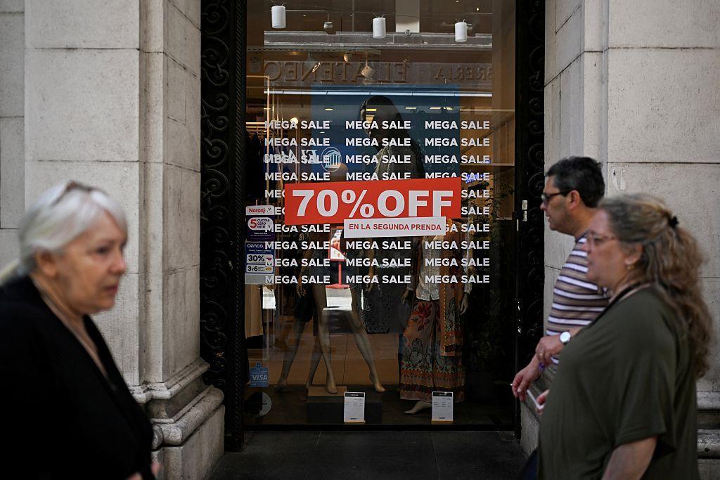 Personas caminan frente a un cartel de "70% OFF" en un comercio en Argentina