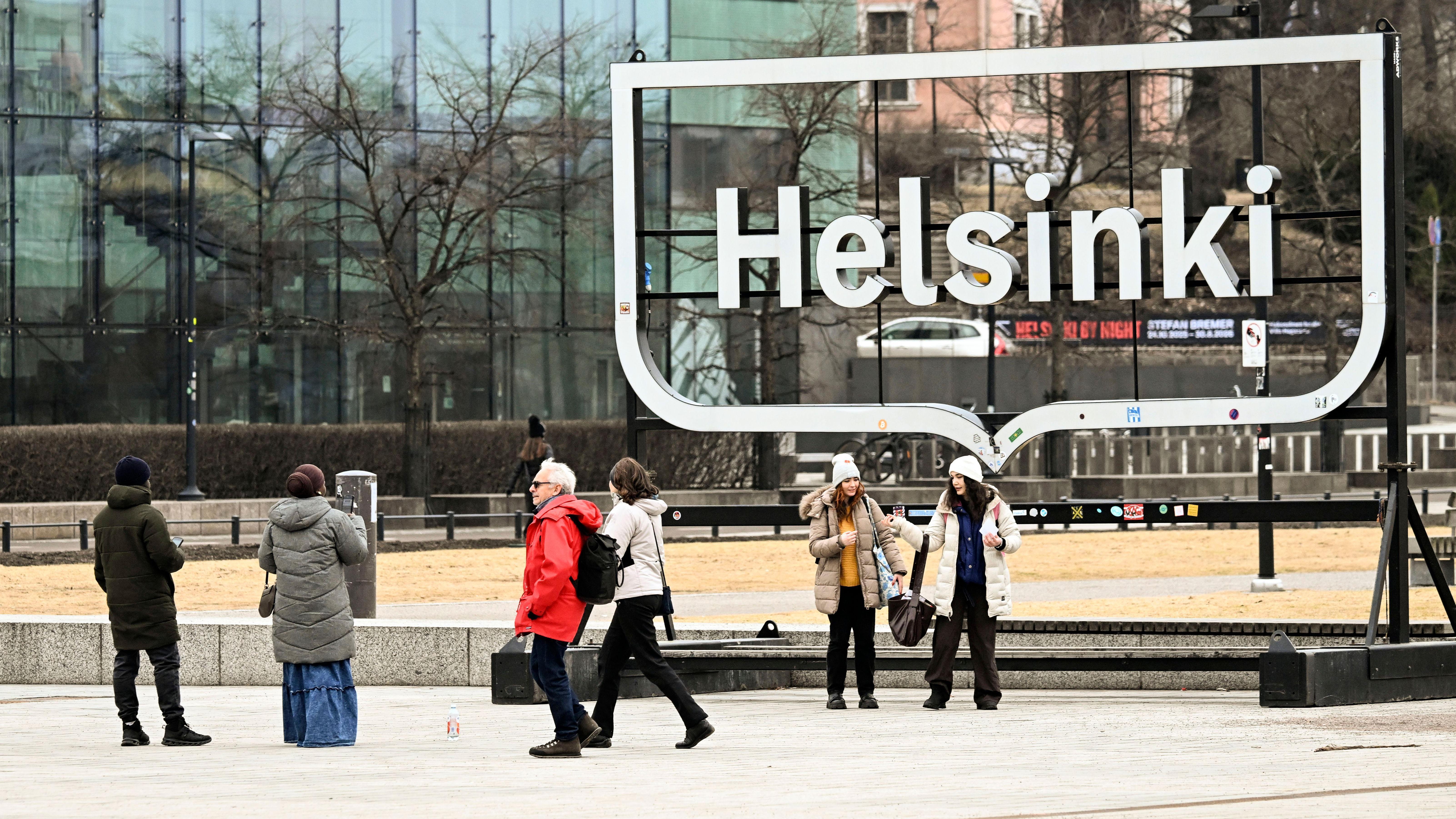 Ljudi u jaknama i kapama šetaju ulicama Helsinkija