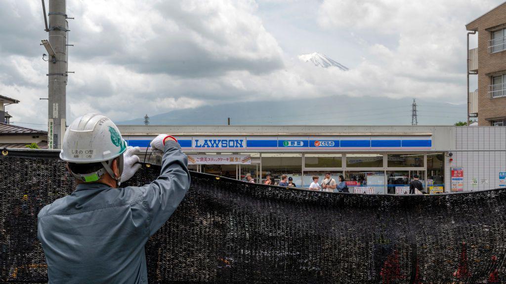 Trabalhador instala uma barreira para bloquear a vista do monte Fuji, no Jap&atilde;o, a fim de deter turistas mal comportados, na cidade de Fujikawaguchiko, no distrito de Yamanashi, em 21 de maio de 2024