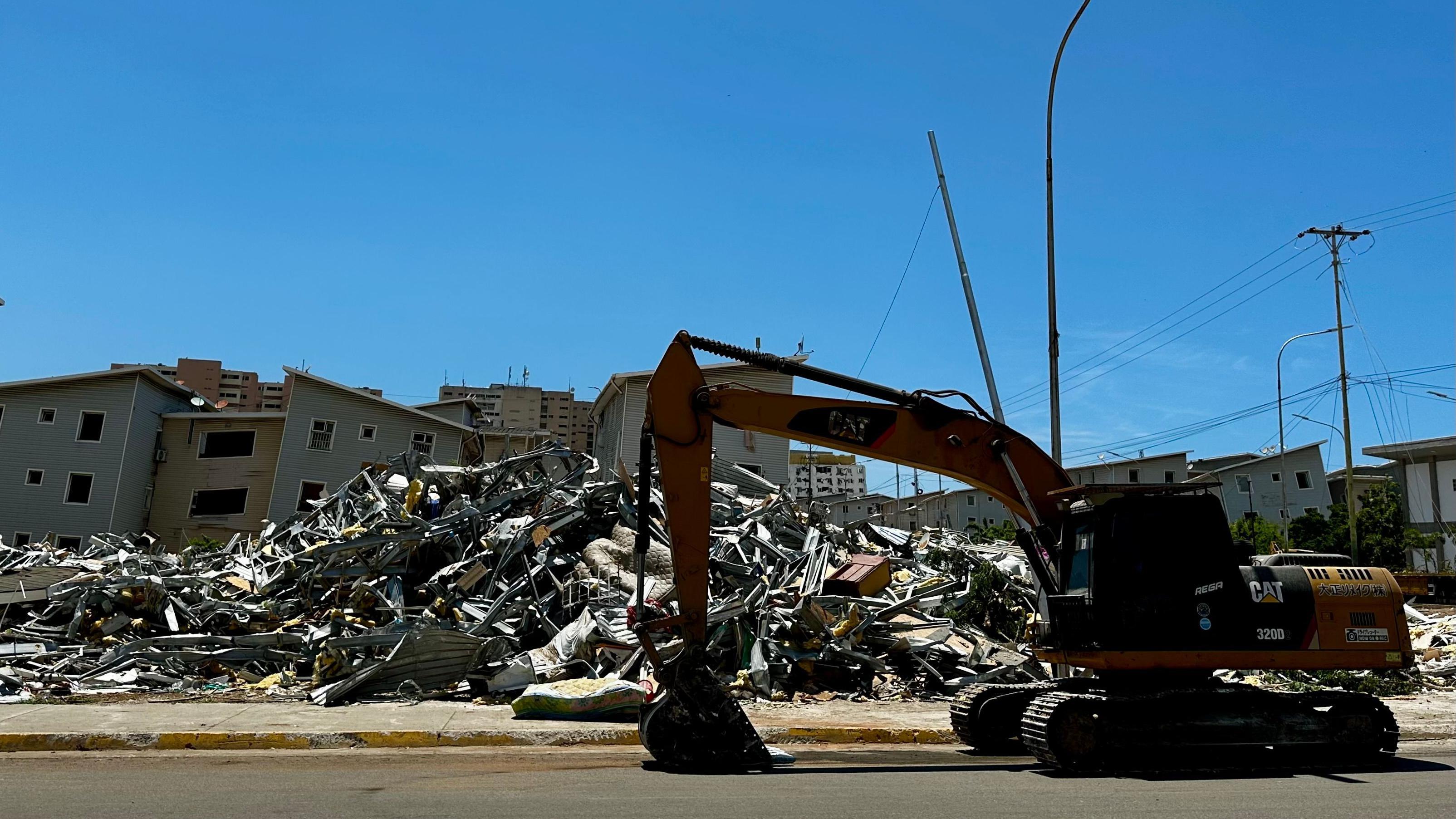 Se ve una grúa frente a varios edificios bajo los escombros. 