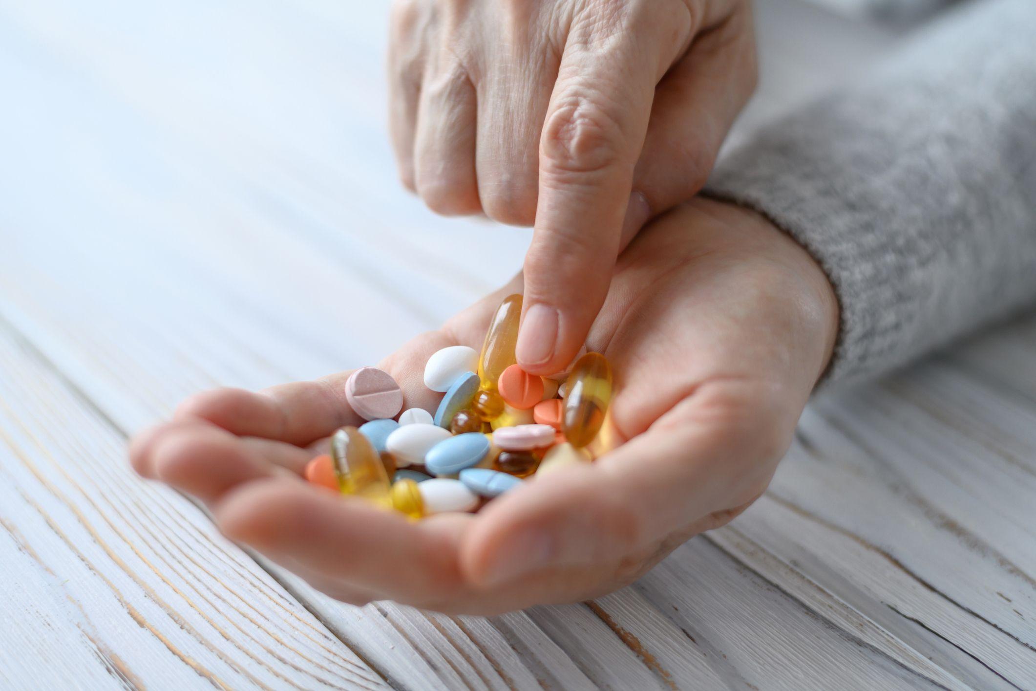 Una mujer mira diferentes tipos de pastillas que tiene en la mano