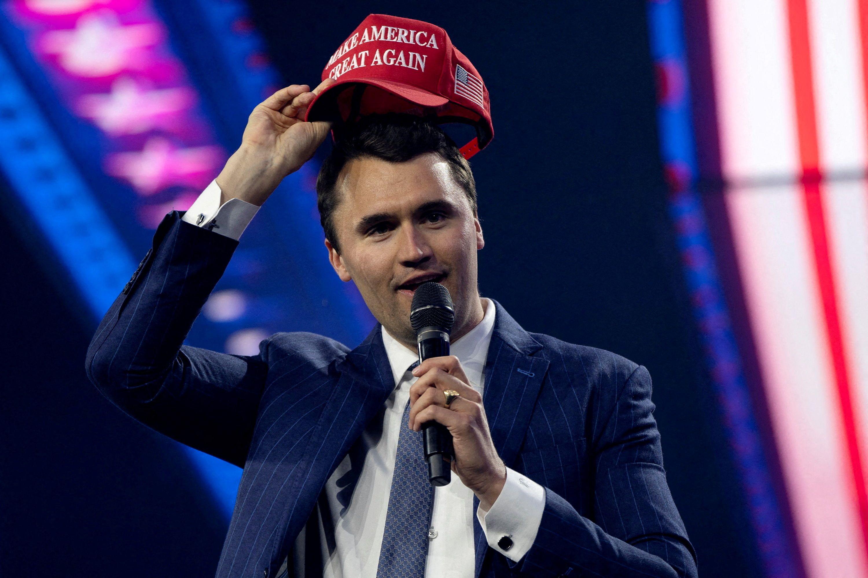 Charlie Kirk loca um bon&eacute; MAGA (Make America Great Again) durante uma confer&ecirc;ncia em 2024 