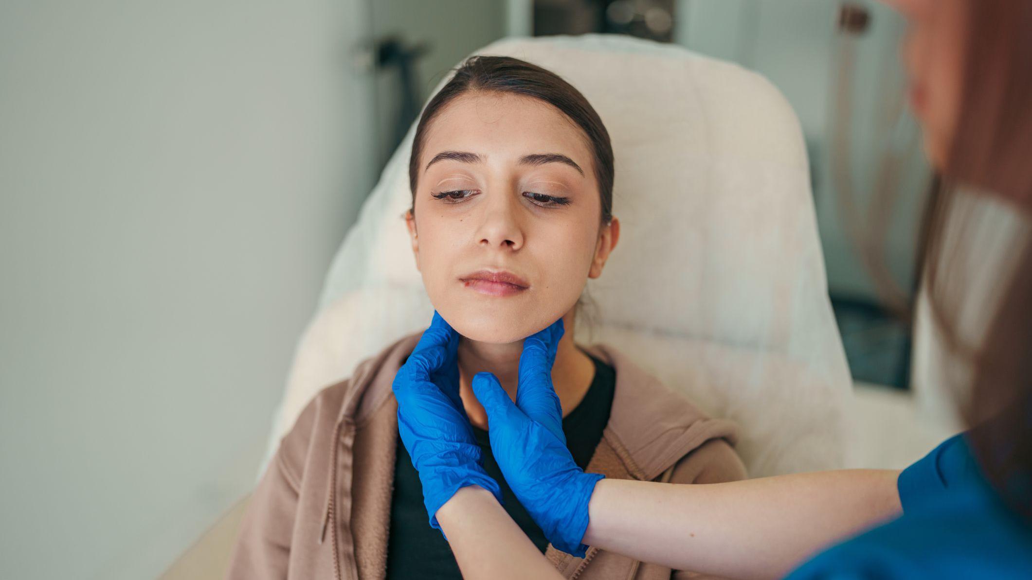 Mulher sentada passa por exame físico da tireoide