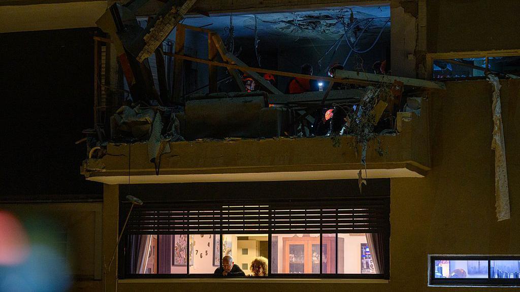 晚上，救援人員在襲擊現場的廢墟中工作，他們戴著頭燈。