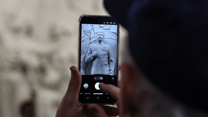 Un hombre fotografía la nueva estatua de Stalin.