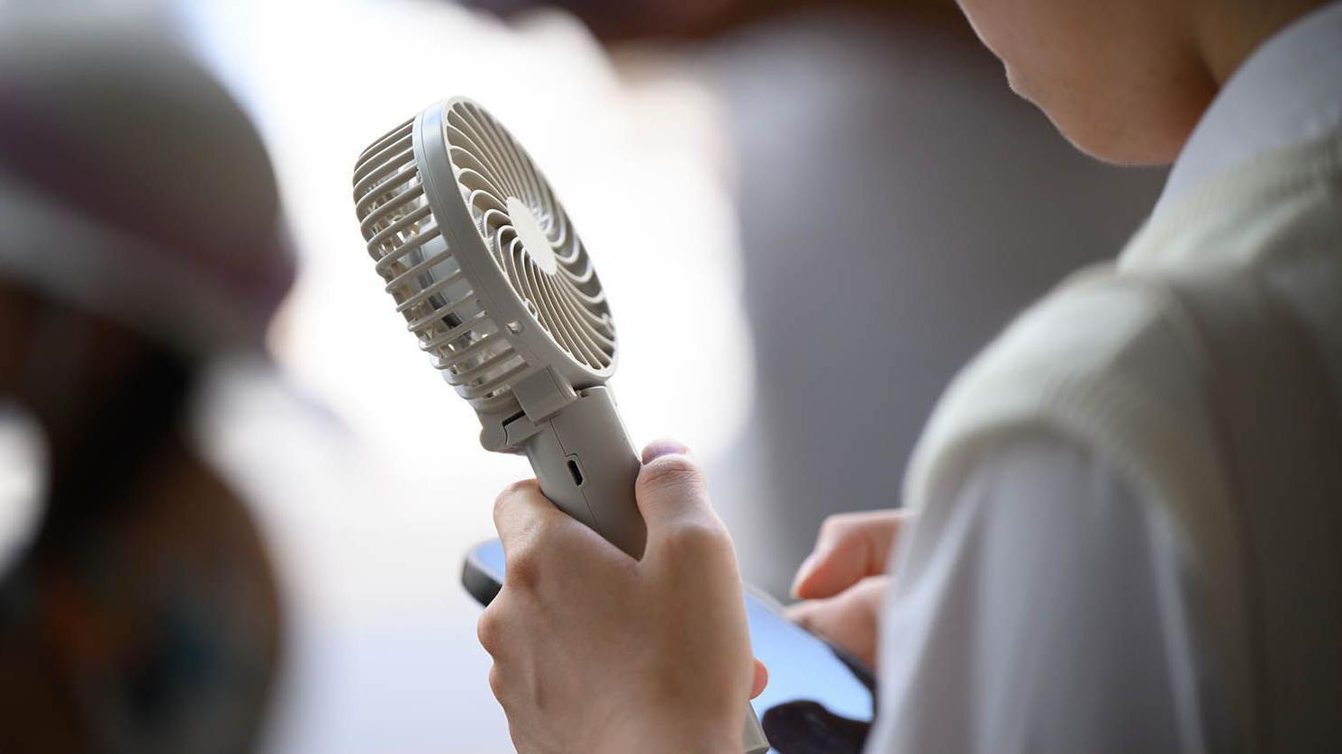 一個人手持一把小風扇