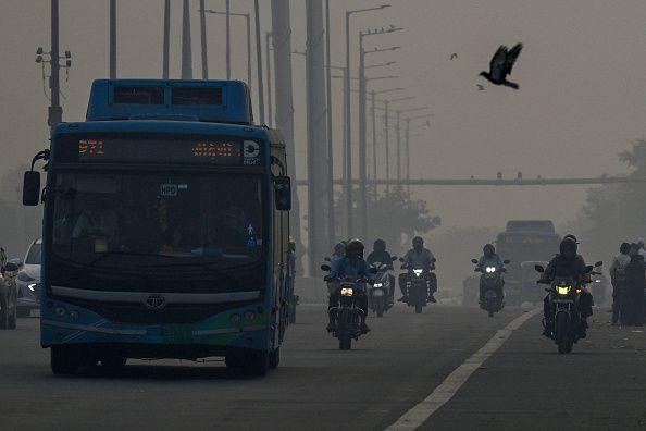 Para komuter berkendara di tengah kabut asap tebal di New Delhi pada 21 Oktober 2025, saat kabut menyelimuti cakrawala kota sehari setelah perayaan Diwali, festival lampu Hindu.