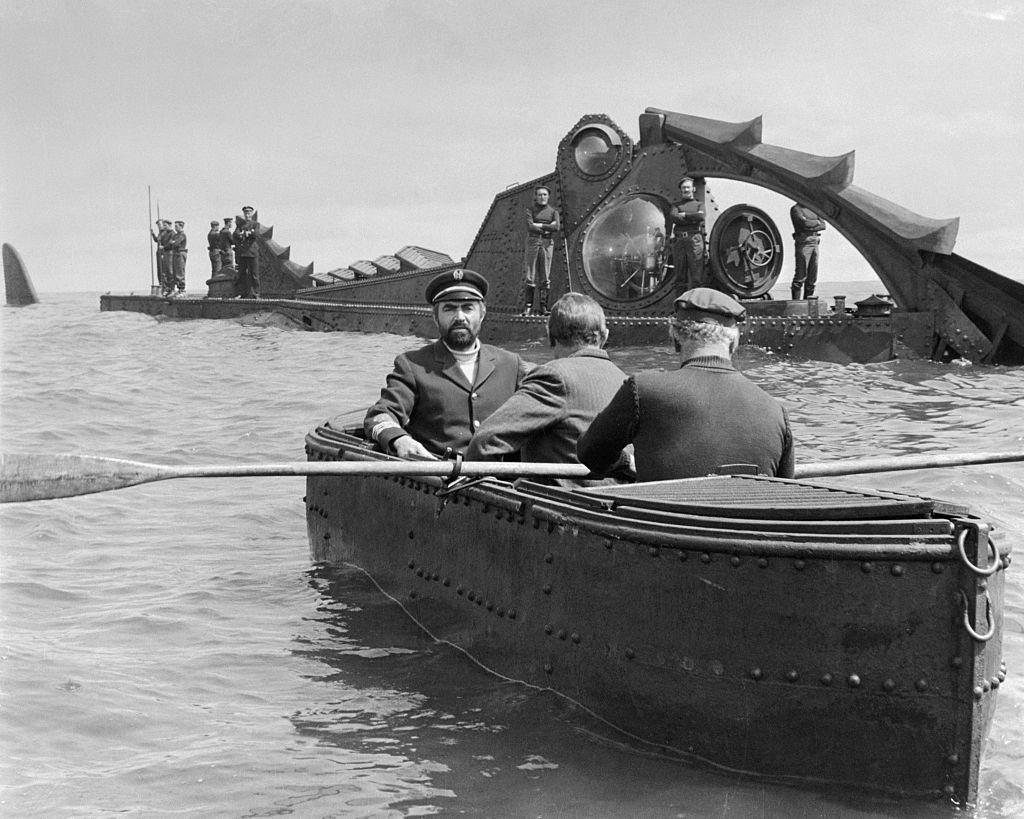 Escena de la película Veinte mil leguas de viaje submarino, basada en la novela de Julio Verne, en la que aparece el submarino Nautilus.
Se observa al capitán Nemo en una barcaza acompañado de dos hombres junto al submarino Nautilus.