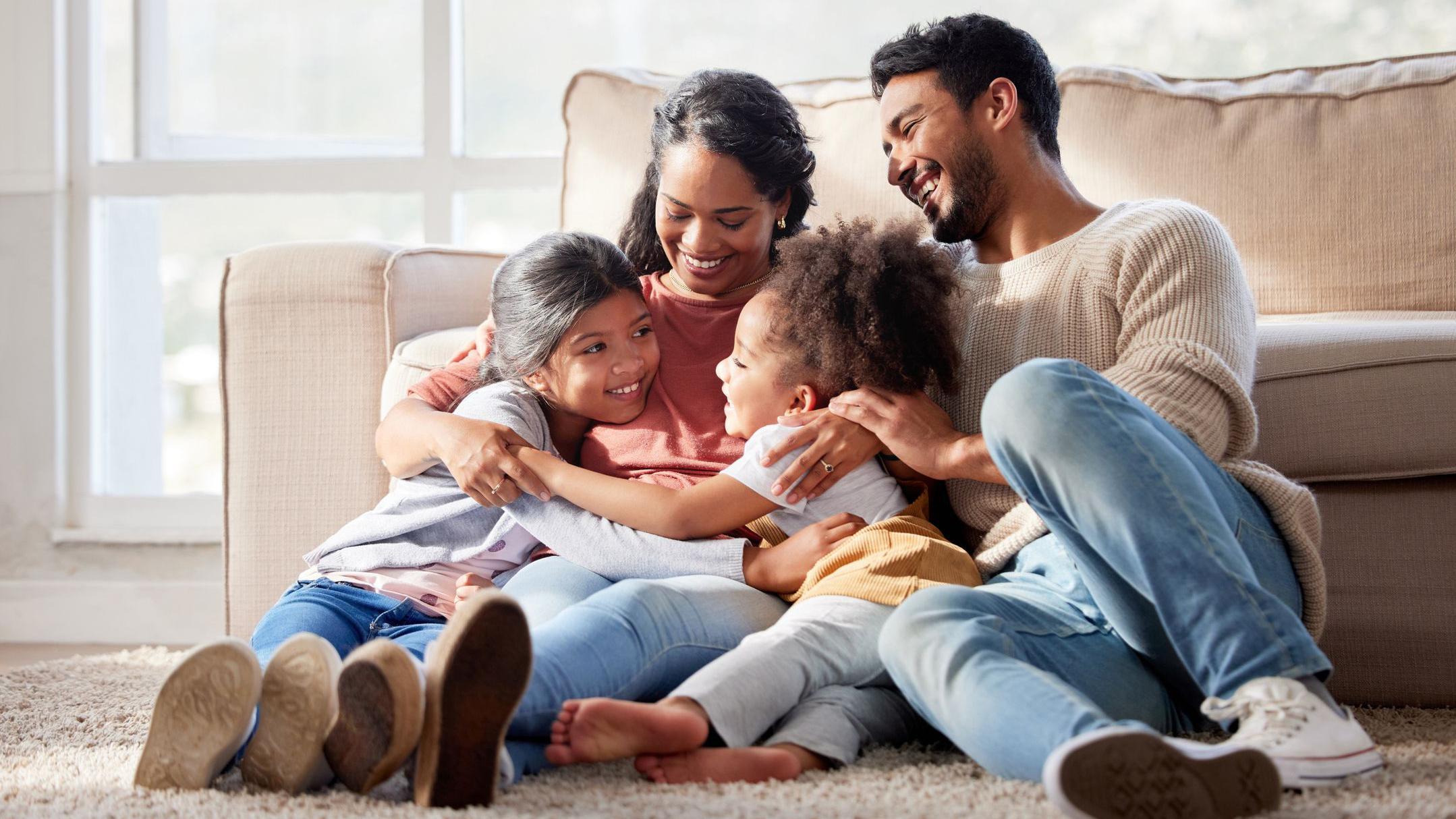 Familia feliz con dos hijas abrazando a su madre y creando vínculos en casa.