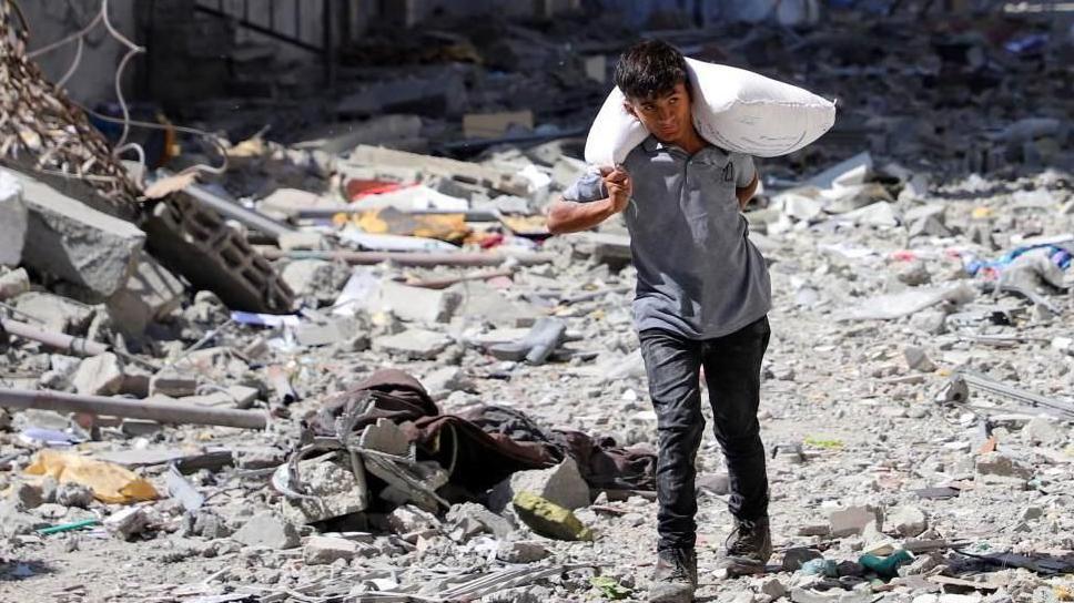 صبي فلسطيني يحمل كيس دقيق