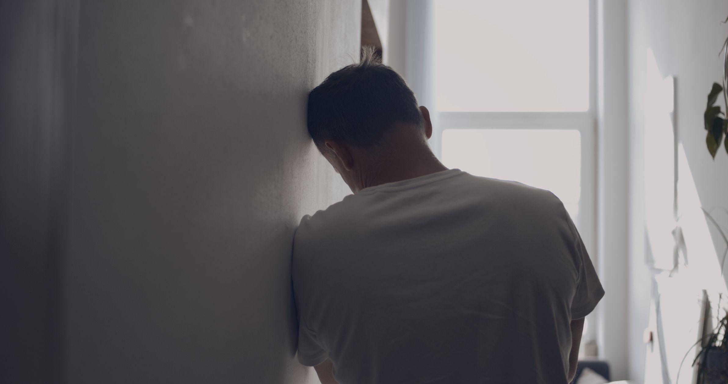 الرجال أيضاً ضحايا العنف الأسري.. لماذا يصمتون؟ 1 رجل حزين في الردهة. يستند إلى الحائط - صورة فوتوغرافية.