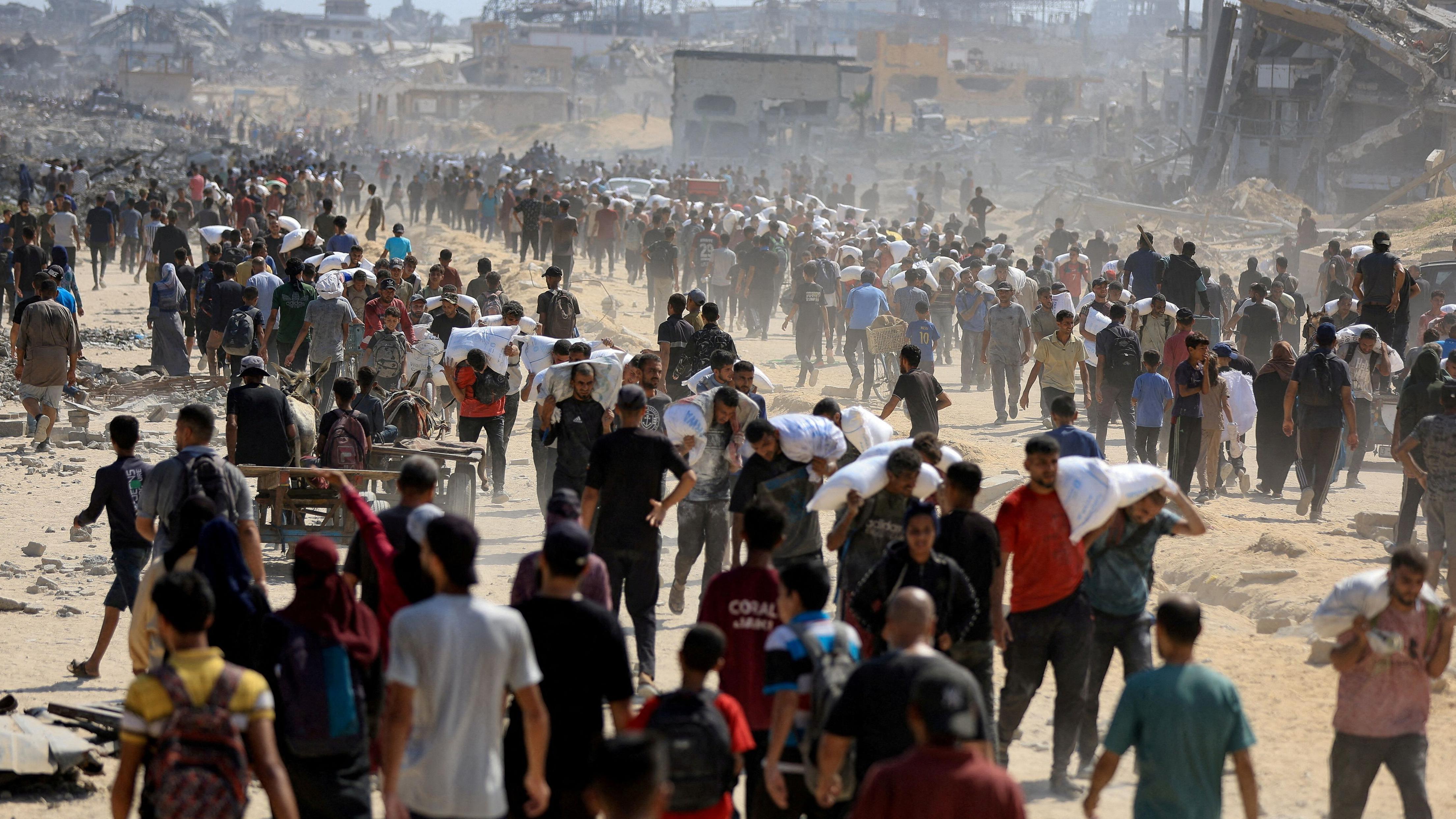فلسطينيون يحملون مساعدات في بيت لاهيا شمال قطاع غزة في 20 يوليو/تموز 2025