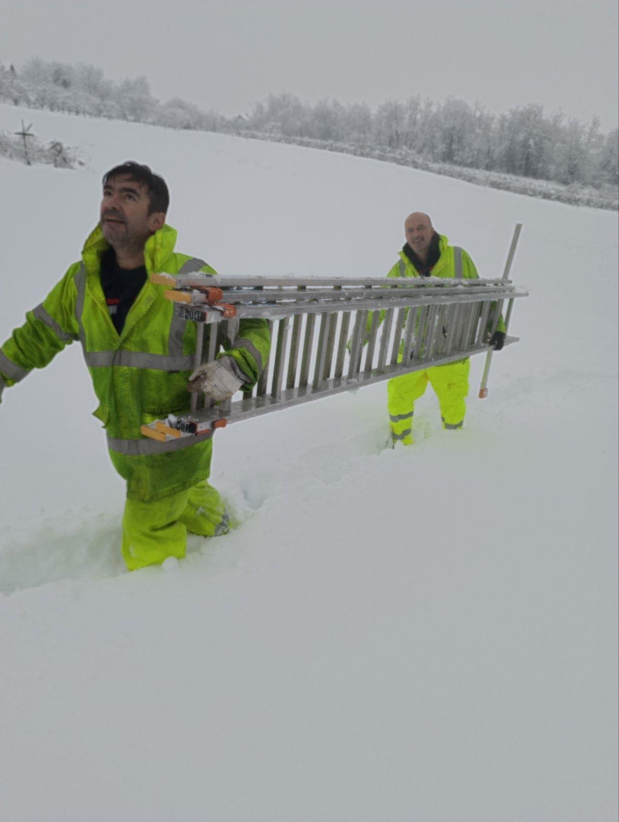 Radnici u snegu nose merdevine