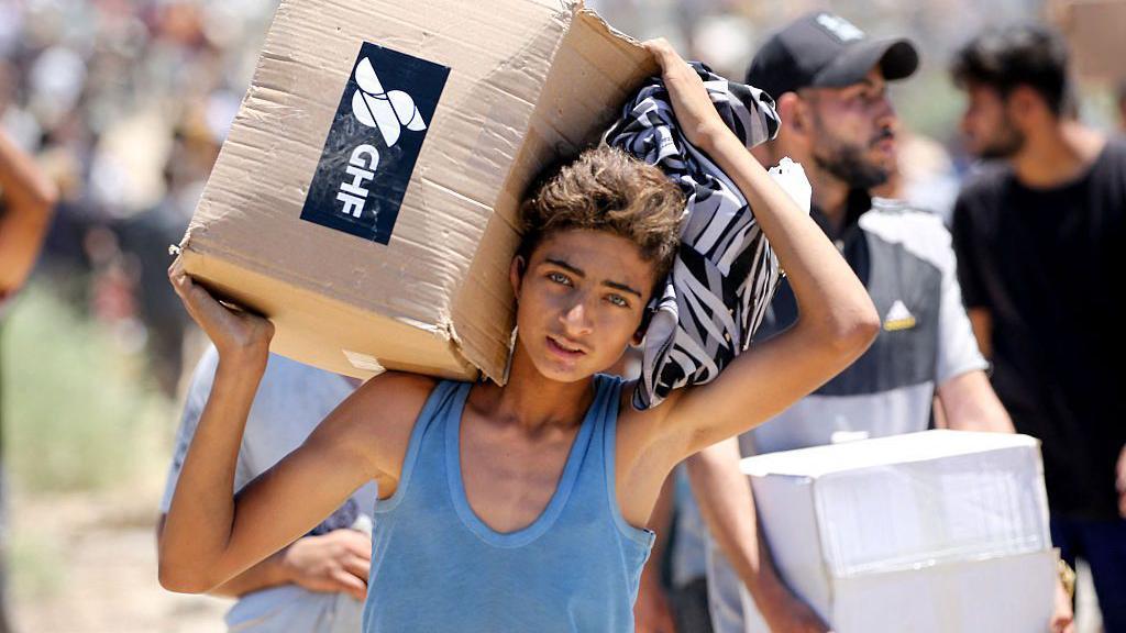 Un joven carga con una caja de ayuda humanitaria.