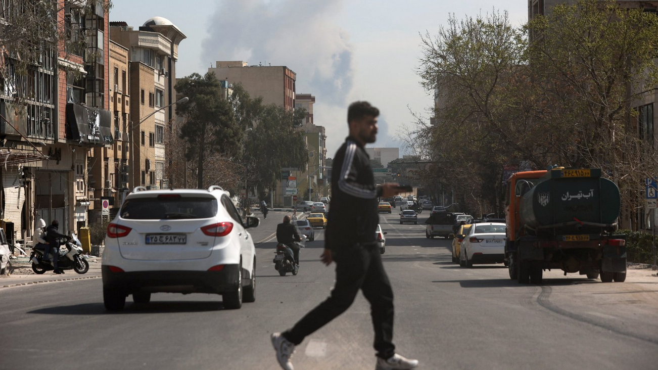 Muškarac u tamnoj odeći prelazi ulicu u Teheranu