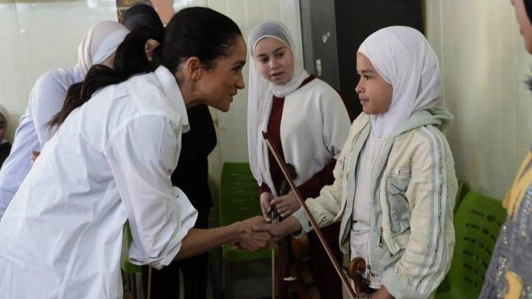 ميغان تصافح عازفة كمان صغيرة في حضور آخرين.