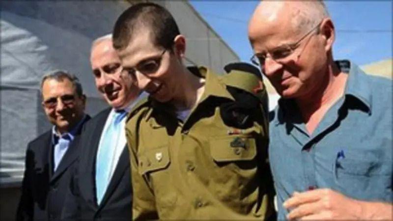 Mladić u zelenoj uniformi sa trojicom starijih muškaraca
