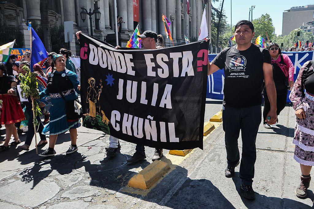 Pablo San Martín Chuñil, hijo de Julia Chuñil, sostiene una bandera que dice "¿Dónde está Julia Chuñil?", en una manifestación en Santiago. 