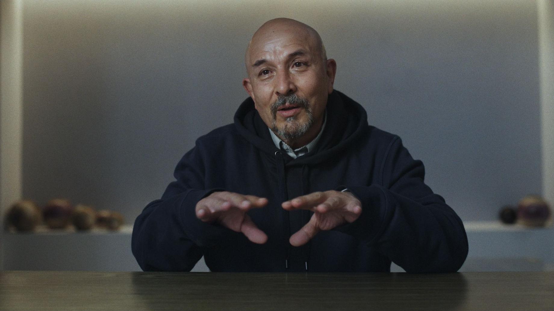 César Fierro sentado durante una entrevista del documental La Libertad del Fierro d2024. Está calvo y tiene barba canosa. Mueve las manos al hablar.